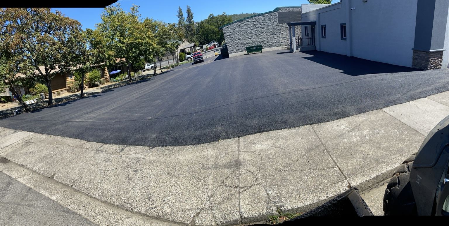Wide asphalt parking area beside a light-colored building.