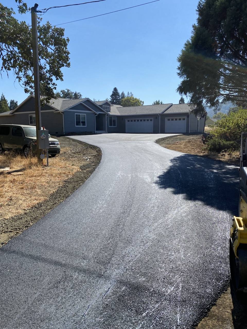 Curved asphalt driveway leading to a home with three garage doors.