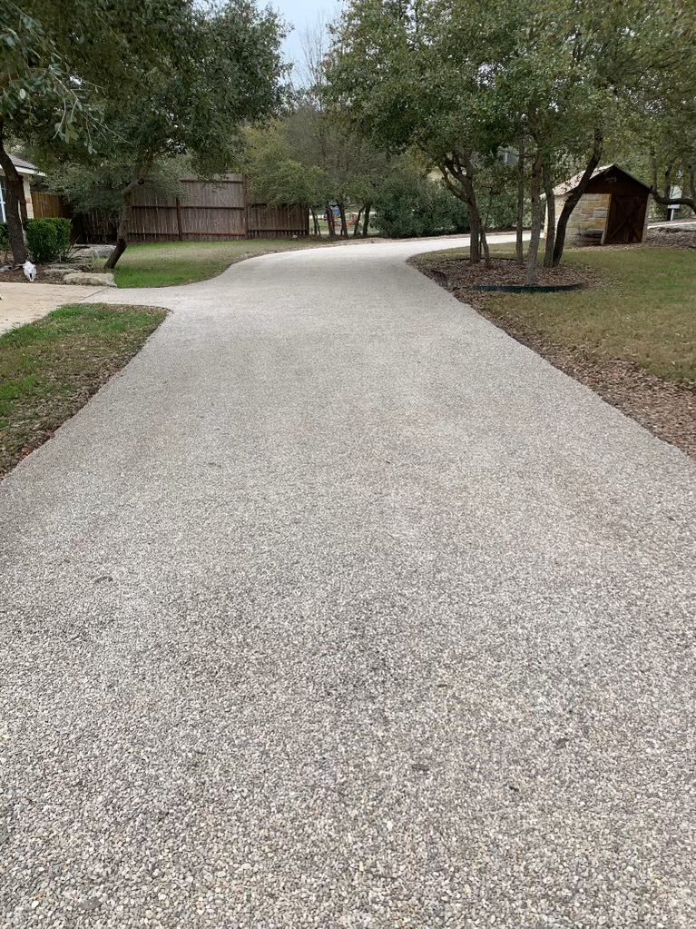 Chip seal driveway winding between trees and landscaped edges.